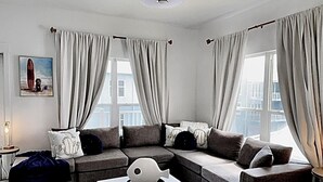 A modern living room with a sectional sofa, a white coffee table, and a ceiling fan. - 4 Beds/4Baths ROOFTOP! Gorgeous MODERN 360 degree views STEPS TO THE BEACH! (Pensacola Beach)