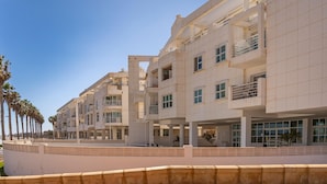 A modern multi-story hotel with a clean, geometric facade, large windows, and a central courtyard with palm trees.