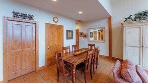 Un comedor con una mesa y sillas de madera, un reloj en la pared y un aparador con objetos decorativos.