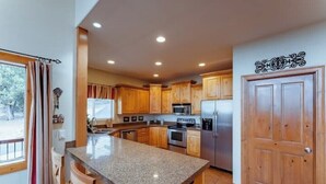 Una cocina con armarios de madera, encimeras de granito, electrodomésticos de acero inoxidable y una puerta de madera.