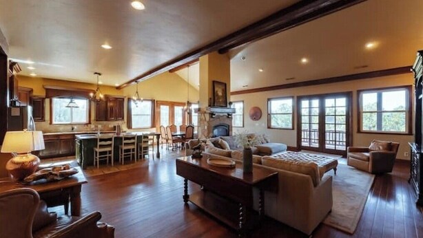 A spacious living area with a fireplace, a dining area, and large windows providing natural light.