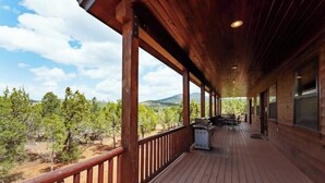 A wooden deck with a railing, overlooking a mountainous landscape.