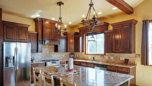 A spacious kitchen with granite countertops, stainless steel appliances, and dark wooden cabinets.