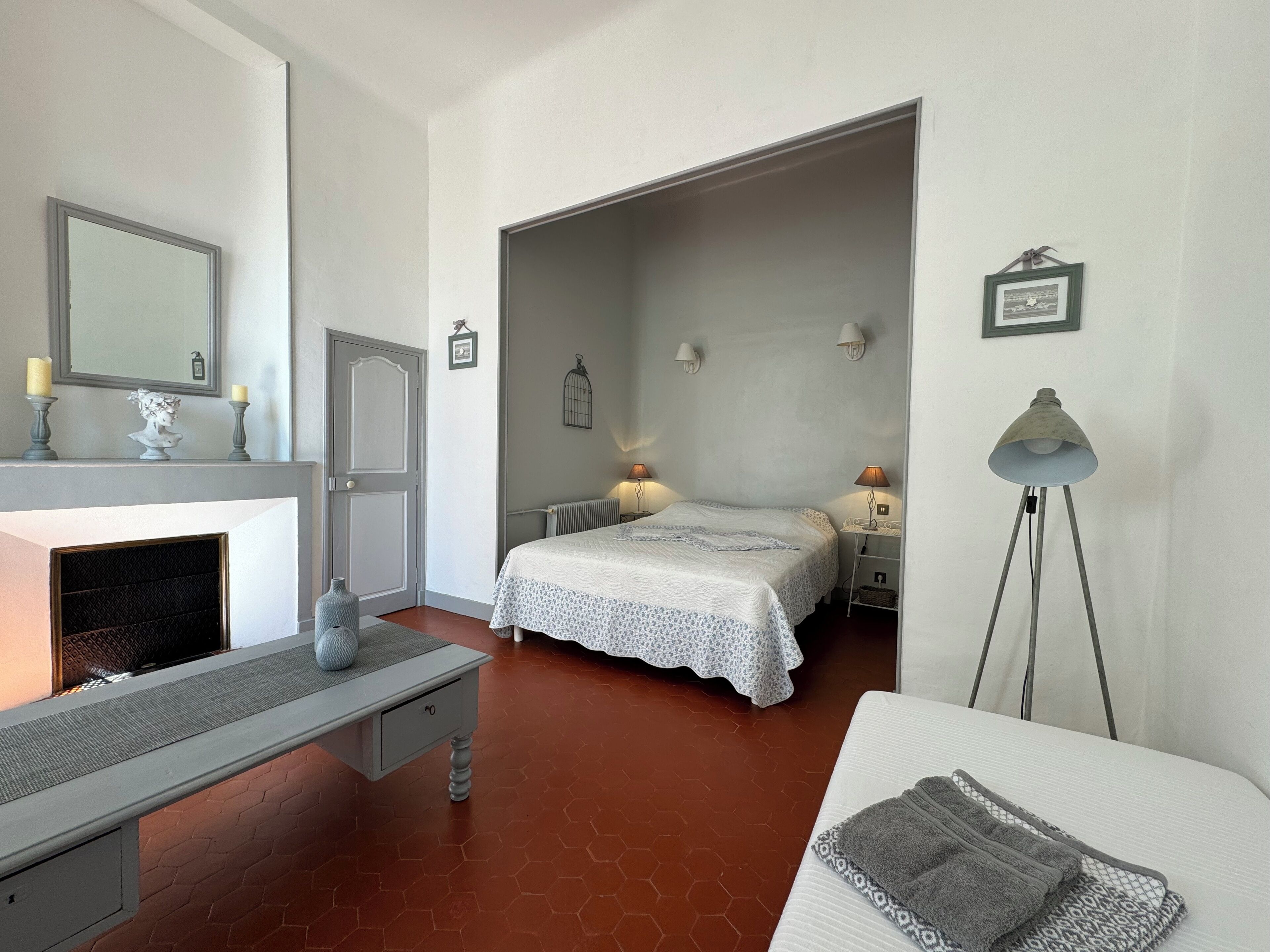 Un dormitorio con cama, lámparas de noche, mesita de noche, cómoda, espejo y lámpara de pie.