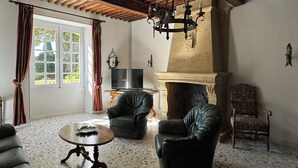 Un soggiorno con camino, poltrone in pelle, televisione e lampadario.