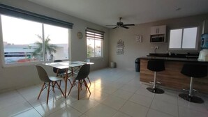 A spacious kitchen with a dining area, large windows, and a ceiling fan.
