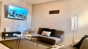 A living room with a flat-screen TV, a sofa, a coffee table, and a rug.