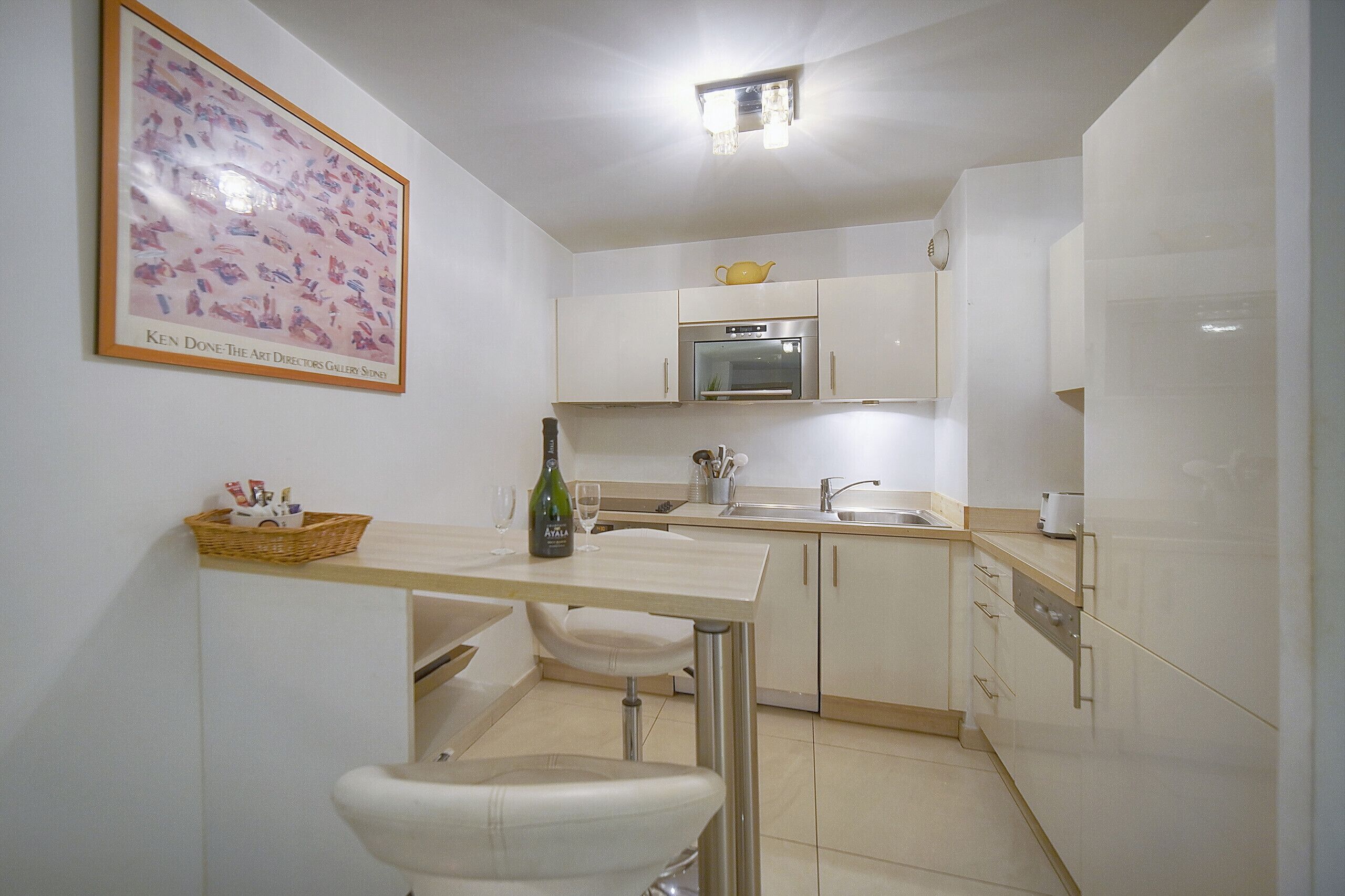 Een moderne keuken met witte kasten, een roestvrijstalen oven en een klein eiland met krukken.