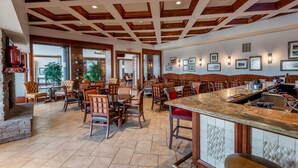 Un vaste espace dédié à la salle à manger, avec des poutres en bois au plafond, de nombreuses tables et chaises, ainsi qu’un comptoir de bar.