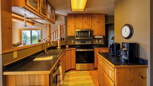 A kitchen with wooden cabinets, a microwave, a stove, and a coffee maker. - Mountain Escape by Terry Peak (Lead)