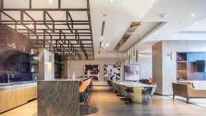 A modern kitchen with a marble island, a dining area with a long table and chairs, and a bar area with stools. - High End 6 people Apartment Islington Etobicoke (Toronto)