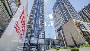 A modern high-rise building with a glass facade, surrounded by other high-rise buildings. - High End 6 people Apartment Islington Etobicoke (Toronto)