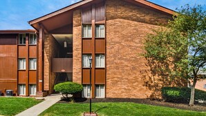 A modern brick building with a flat roof, large windows, and a small tree in the front yard. - Furnished Resort Style Apartment w/ WIFI & Parking (Columbus)