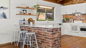 A kitchen with a brick island, white cabinets, and a window overlooking a garden.