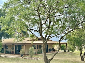 A single-story building with a flat roof, surrounded by a grassy lawn and trees.