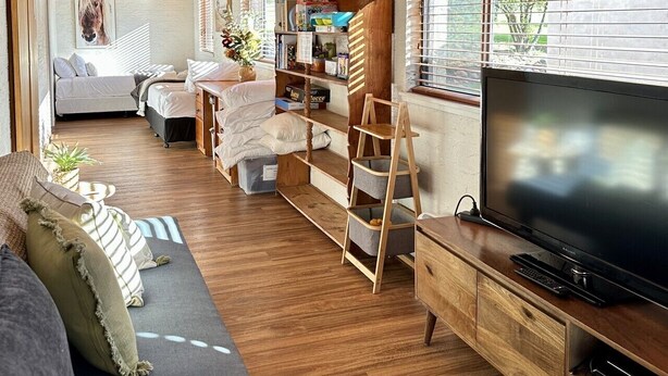 Een gezellig interieur met een houten plafond, een bank, een televisie en een boekenplank.