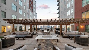 A rooftop patio with outdoor seating and a view of the city skyline.