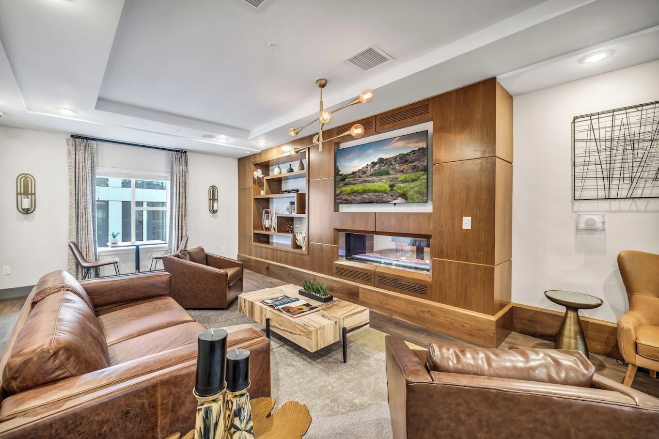 A modern living room with leather sofas, a coffee table, and built-in shelving.