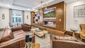 A modern living room with leather sofas, a coffee table, and built-in shelving.