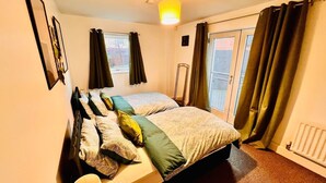 Habitación de hotel con dos camas, una ventana con cortinas, un radiador y un espejo en la pared.