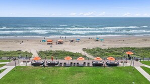 Une vue sur la plage avec un espace patio comprenant des sièges d’extérieur et des parasols.