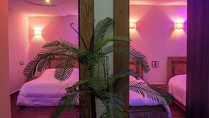 Een kamer met twee bedden, een houten vloer en een bloempot in het midden.
