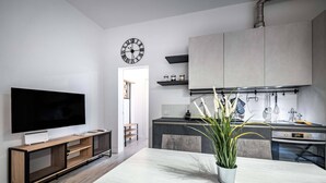 Eine moderne Küche mit Einbauofen, einem Essbereich mit großem Tisch und einem Fernseher auf einem Holzboden.