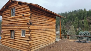 A log cabin with a simple, rustic design, featuring two windows and a small porch area.