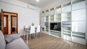 Un salon moderne comprenant un canapé, une table à manger, des chaises et des étagères intégrées.