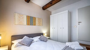 Un lit bien fait, avec des oreillers, une lampe de chevet et une grande armoire dans une chambre d’hôtel.
