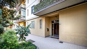 A multi-story residential building with a tiled entrance, a small garden area, and balconies with plants. - YiD bright with parking (Firenze)