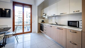 A modern kitchen with a large window, a dining area with a table and chairs, and a flat-screen TV mounted on the wall. - YiD bright with parking (Firenze)