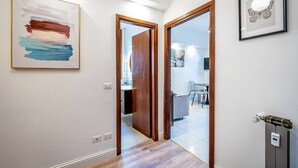 A hallway with a wooden floor, a framed abstract painting, and a framed butterfly artwork on the wall. - YiD bright with parking (Firenze)