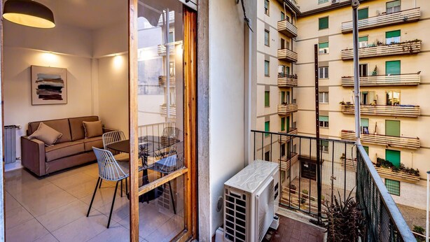 A balcony with a view of a residential building, a table with chairs, and a sofa inside a room. - YiD bright with parking (Firenze)