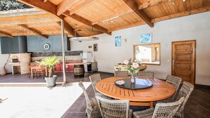 An outdoor dining area with wicker chairs and a round wooden table, a barbecue grill, and a stone oven in the background. - Amazing home in Saulce sur Rhône (Saulce sur Rhône)
