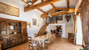 A spacious dining area with a wooden table and chairs, a staircase leading to an upper level, and a stone wall. - Amazing home in Saulce sur Rhône (Saulce sur Rhône)