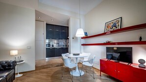 Un espace de vie moderne comprenant une table à manger, des chaises, un meuble de rangement rouge et, au fond, une cuisine.