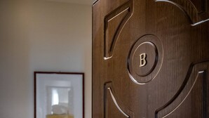 Une porte en bois avec une poignée en laiton et un trou de serrure, un tableau encadré accroché au mur, et une commode en bois avec des tiroirs.