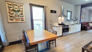 Un salón espacioso con una mesa de comedor de madera, una cocina con armarios blancos y un sofá de cuero marrón.