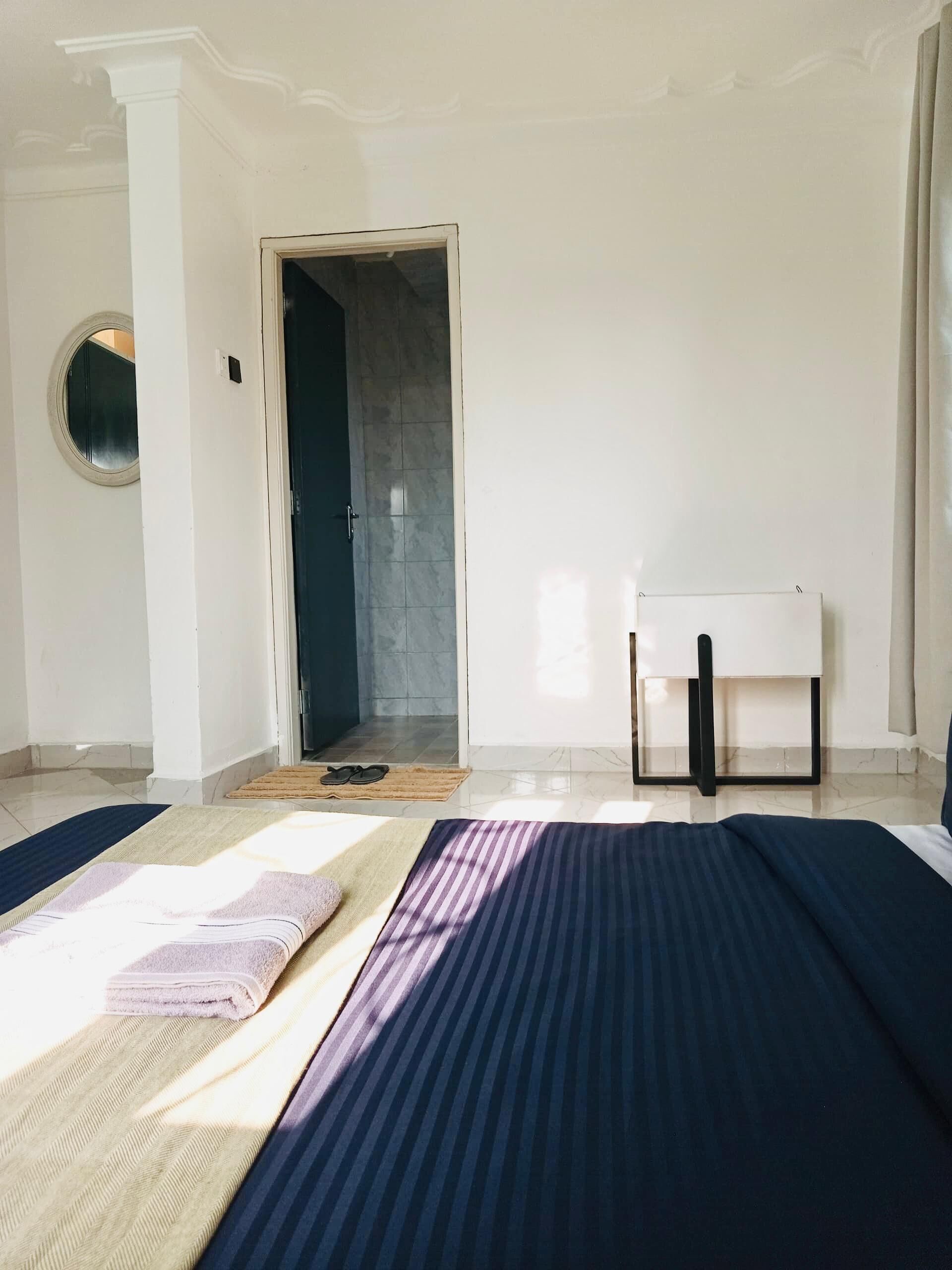 A room with a bed, a small table, and a door leading to a bathroom.