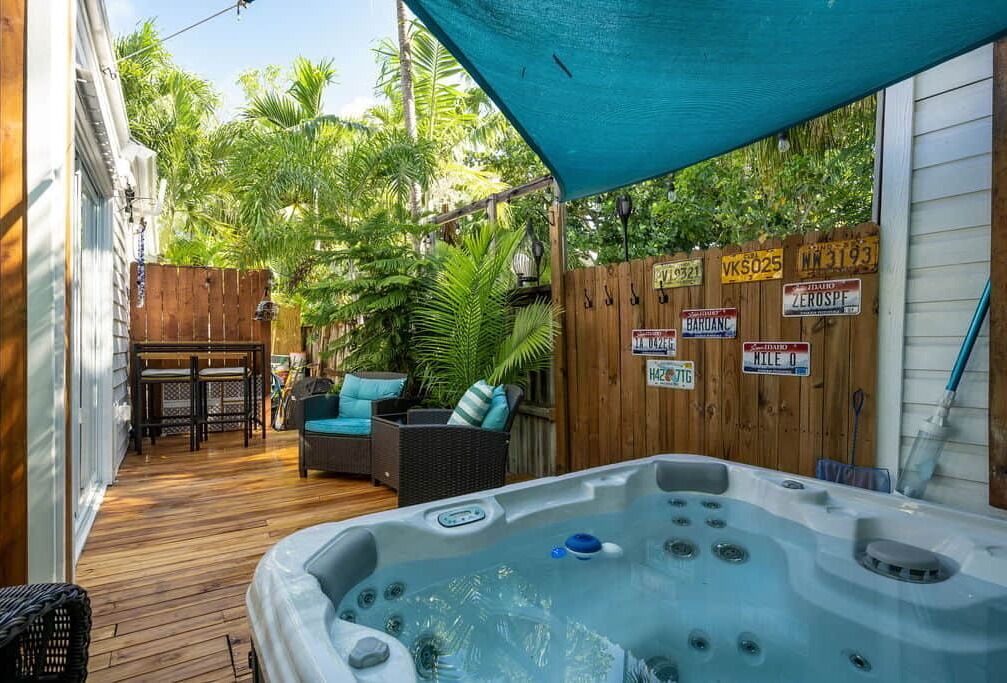 A wooden deck with a hot tub, outdoor furniture, and a covered seating area.