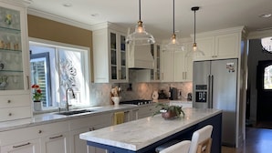 A modern kitchen with white cabinets, a marble island, pendant lighting, and a stainless steel refrigerator. - Gorgeous Solana Beach 3 bd pool, view, perfect for beach & racetrack  (Solana Beach)