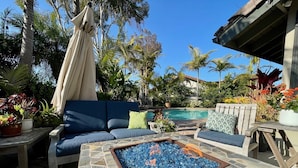 A poolside area with a blue sofa, a stone fire pit, and various potted plants. - Gorgeous Solana Beach 3 bd pool, view, perfect for beach & racetrack  (Solana Beach)