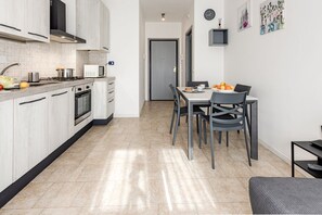 Une cuisine moderne avec des meubles blancs, un coin repas comprenant une table et des chaises, et un four à micro-ondes posé sur le plan de travail.