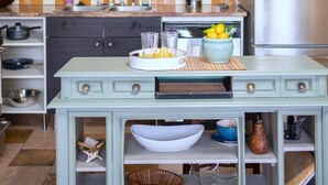 A kitchen with a green cabinet, a tiled backsplash, and a refrigerator.