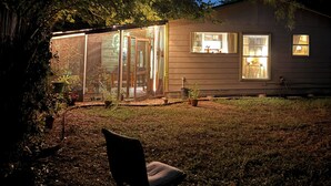 A house with a glass enclosure, a chair, and a table with a glass.