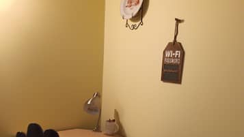 A small office space with a desk, chair, and a wall-mounted Wi-Fi password sign.