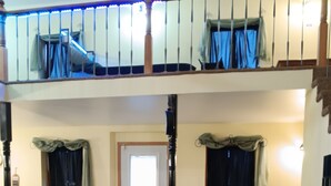 A living room with a sofa, armchairs, and a glass coffee table. There is a staircase with a railing leading to an upper level. - Bank on it! Suite Bank (Sidney)