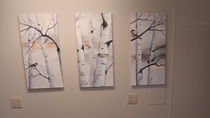 A bedroom with a bed, three wall-mounted paintings of birch trees, and a carpeted floor. - Bank on it! Suite Bank (Sidney)