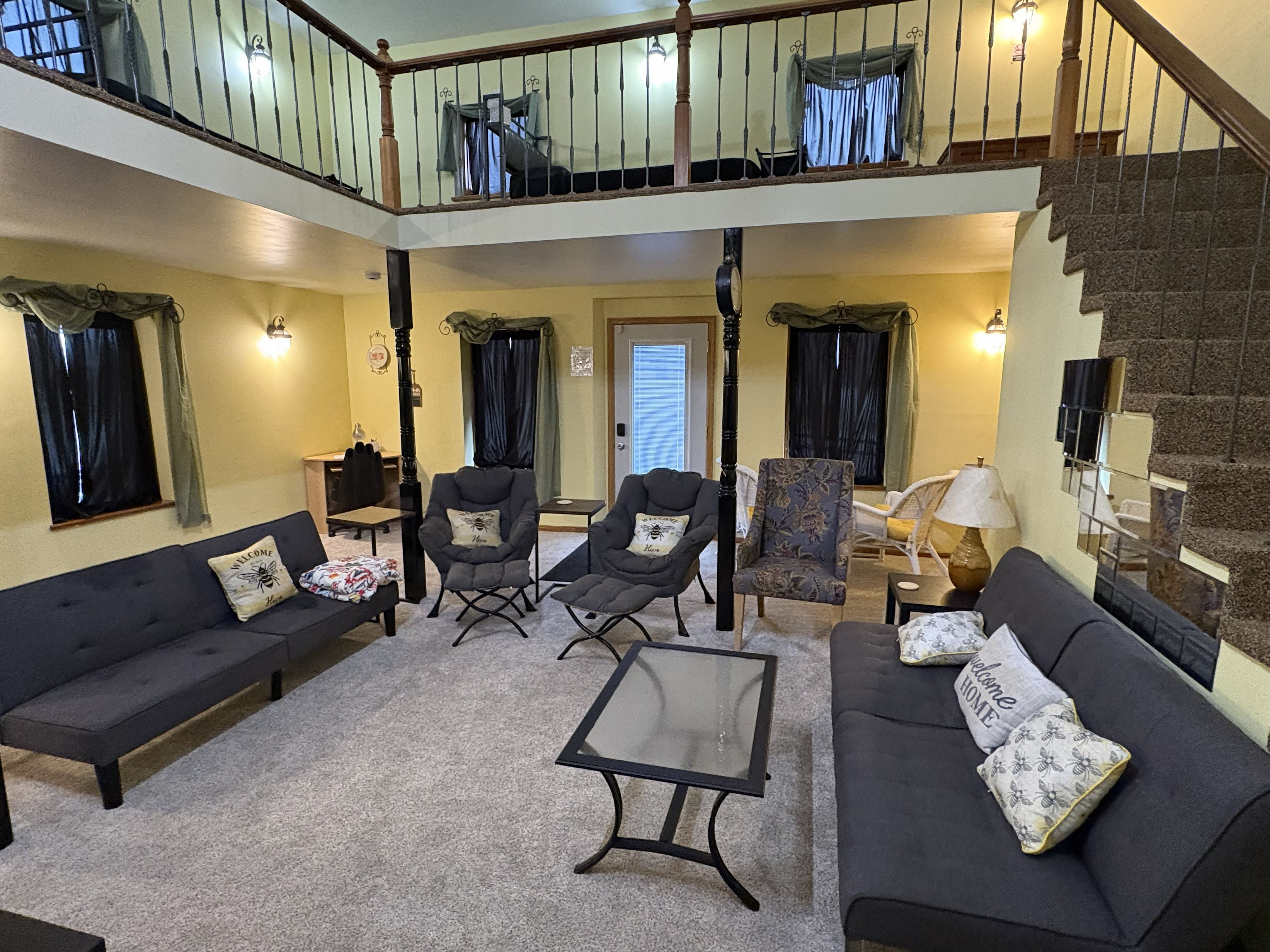 A spacious living area with a high ceiling, a staircase, and a balcony.